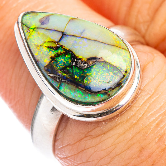 Teardrop opal gemstone in green and blue on a silver ring band, close-up