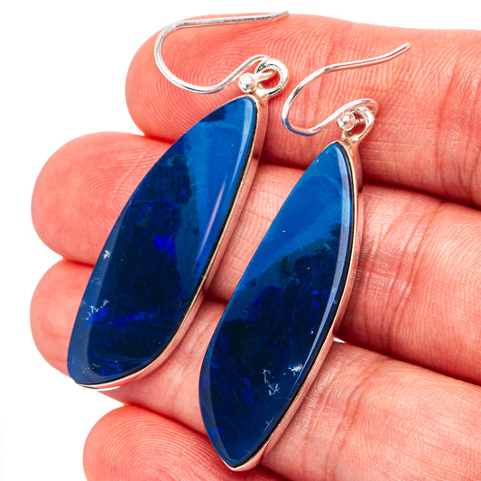 Blue teardrop opal drop earrings on silver hooks, shown close-up in hand