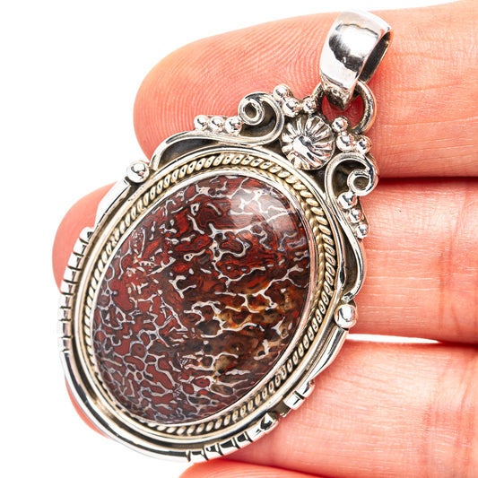 Dinosaur bone pendant in oval sterling silver bezel with red-brown pattern and ornate bail