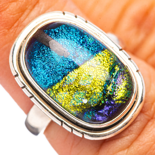 Oval dichroic glass ring with iridescent blue, green, yellow, and silver bezel
