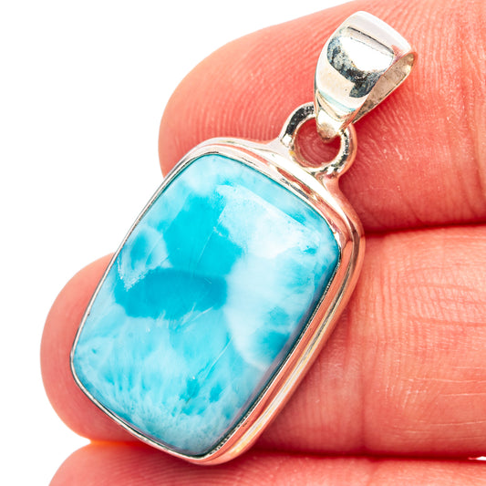 Larimar pendant close-up on finger, oval blue stone in silver bezel with bail