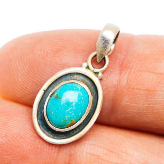 Turquoise oval pendant with silver bezel and loop bail on a dark edge