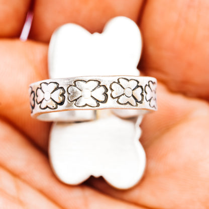 Sterling silver band with repeating floral cutout pattern, adjustable ring