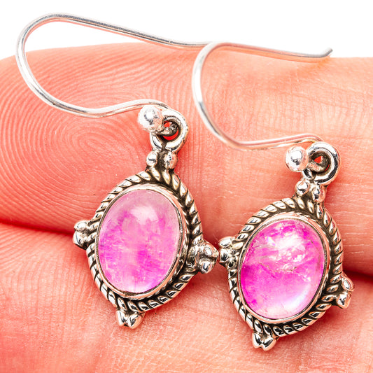 Sterling silver earrings with oval pink moonstone in ornate frame, hook backs visible