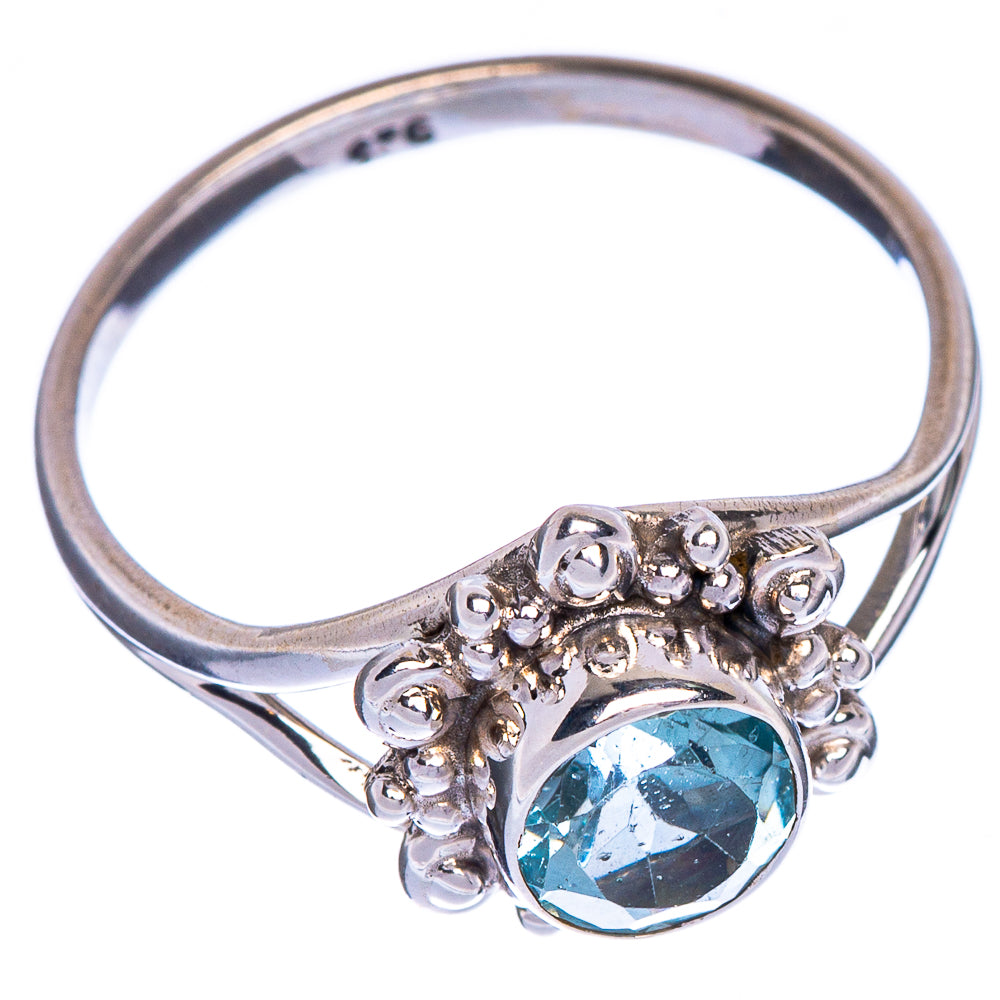Sterling silver ring band with oval blue topaz bezel and decorative side scrolls
