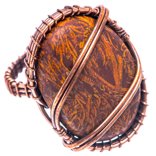 Oval orange-brown jasper cabochon wrapped in oxidized copper, ornate wire ring