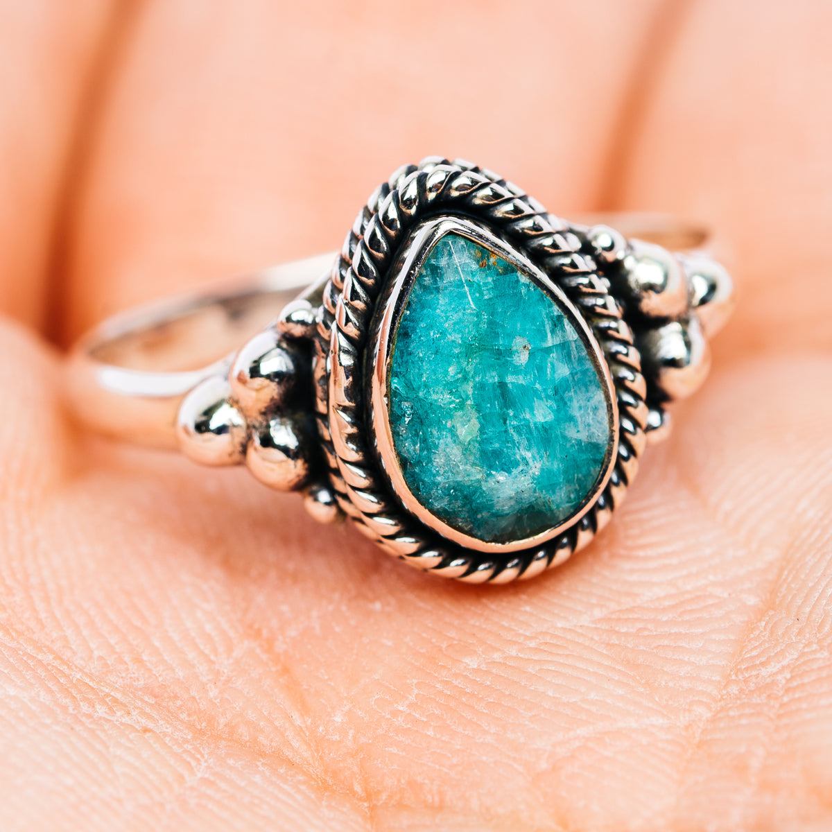 Turquoise-green teardrop stone sterling silver ring with ornate bead and braided band