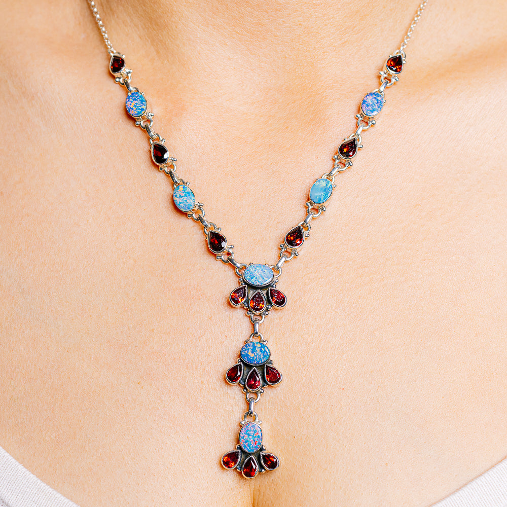 Sterling silver gemstone necklace with blue opal-like stones and red garnet accents