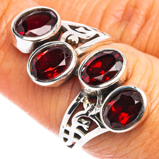 Sterling silver ring with four faceted garnet stones and engraved scroll cutouts.