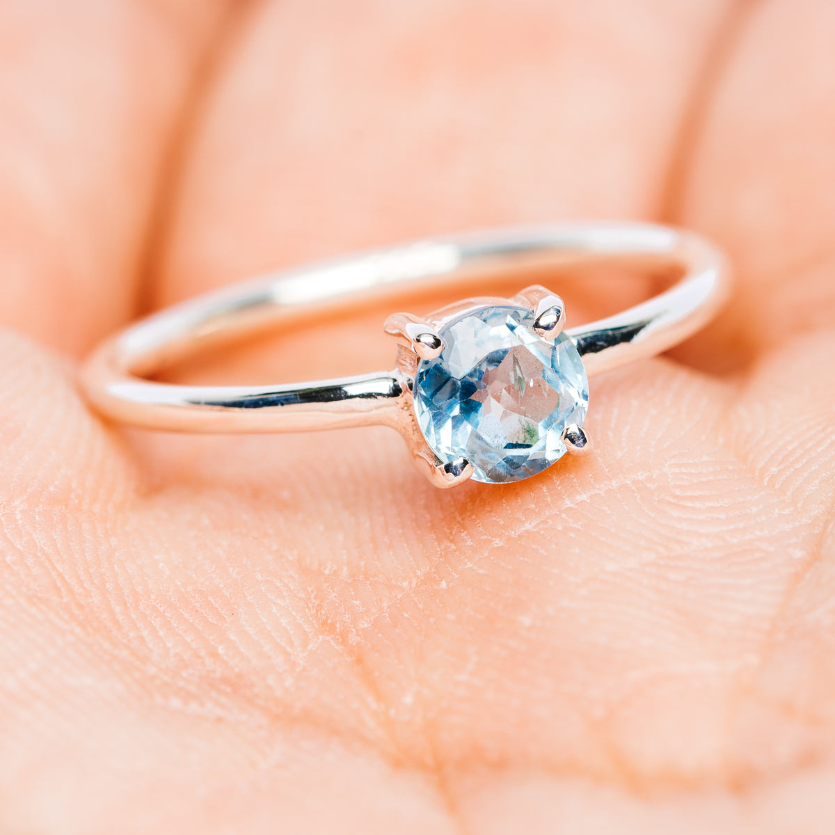 Sterling silver ring with round blue topaz bezel setting and open shank