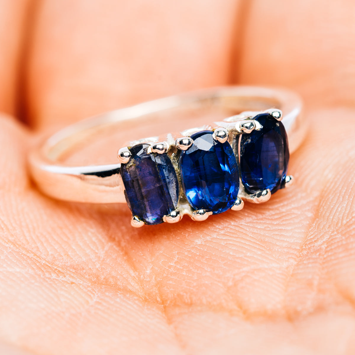Three-stone kyanite band ring with three blue oval stones and silver prong setting
