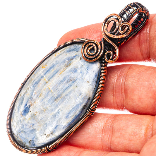 Oxidized copper wire-wrap kyanite teardrop pendant, closeup swirl setting on blue stone