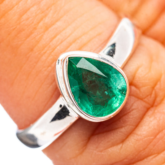 Silver emerald ring showing round green gemstone in bezel on finger, size 7