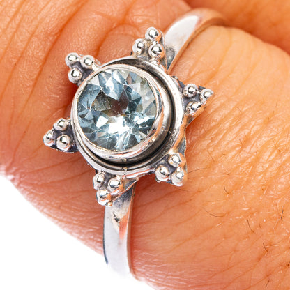 Blue topaz ring close-up: round sky-blue stone in ornate sterling silver prong setting