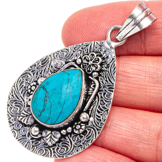 Turquoise teardrop pendant with ornate silver-tone German-silver filigree border and loop top