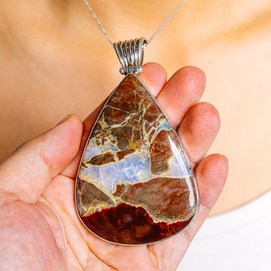 Teardrop jasper pendant held in hand, .925 sterling silver bail, red tan and blue