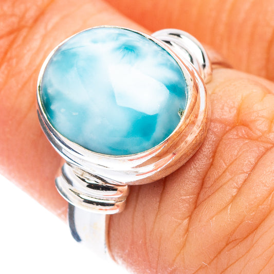 Sterling silver larimar ring on finger, oval turquoise-blue gemstone in round bezel