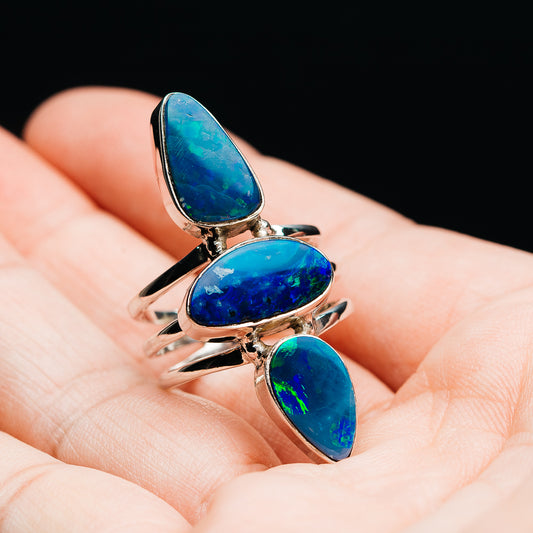 Opal doublet ring with three blue oval opal stones and a silver band