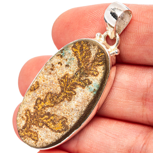 Sterling silver oval pendant with psilomelane dendrite stone, gold-brown and blue flecks.