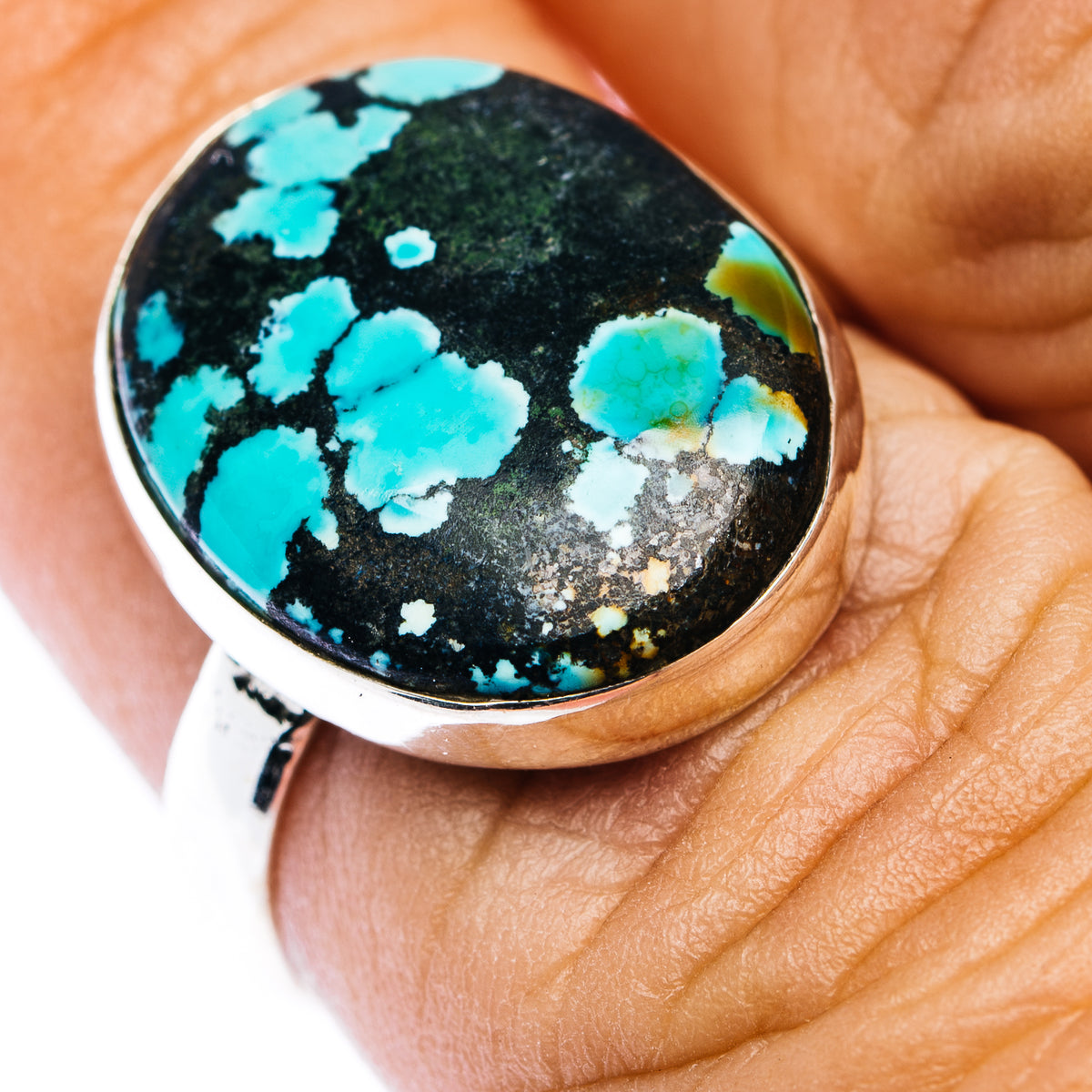 Sterling silver oval turquoise ring with black matrix stone, close-up on finger