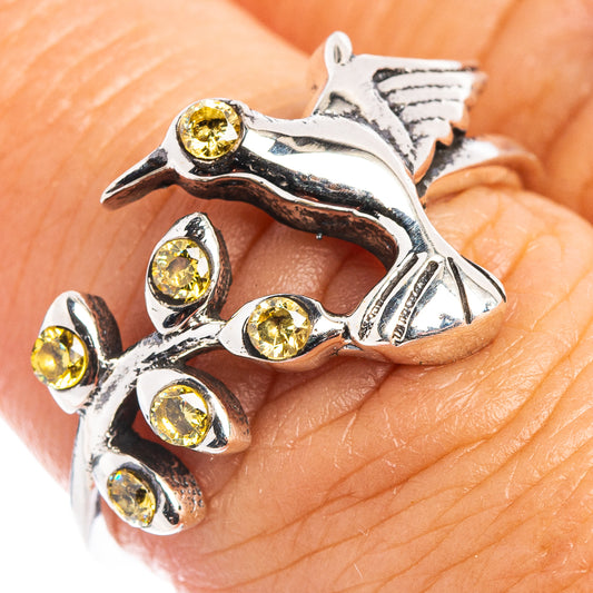 Sterling silver hummingbird ring on finger, with multiple round citrine yellow gems