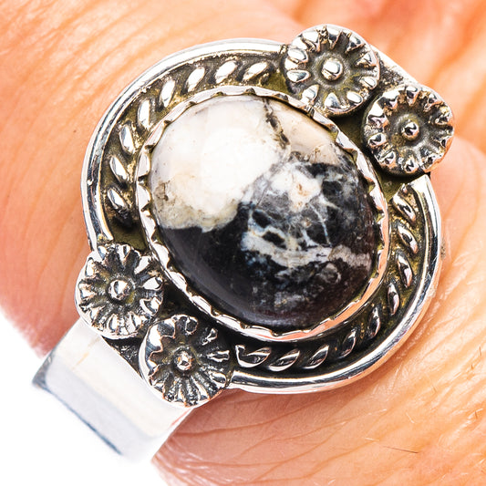 Silver ring with oval white-and-dark stone and floral sunburst bezel, adjustable band
