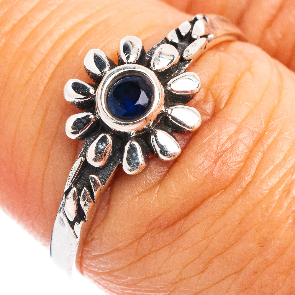 Sterling silver dainty flower ring with blue quartz center, on a hand close-up