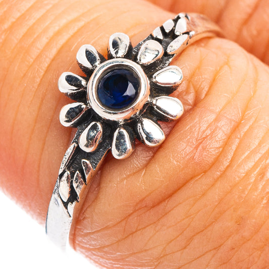 Sterling silver dainty flower ring with blue quartz center, on a hand close-up