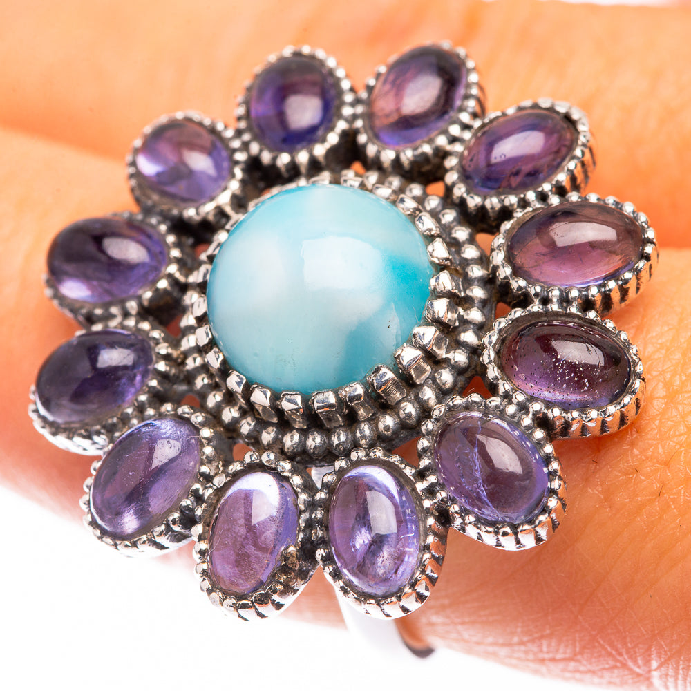 Sterling silver ring on finger with blue oval center stone and purple oval gemstones