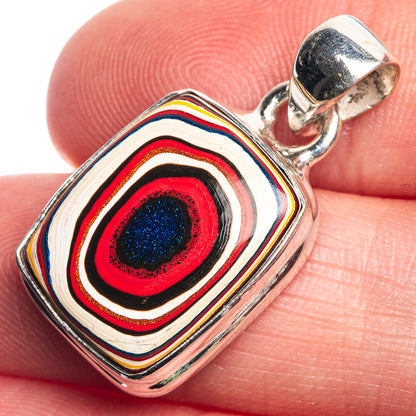 Fordite pendant close-up on bail loop, multicolor striped stone in red blue tones