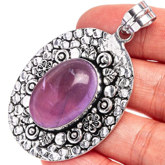 Amethyst cabochon pendant in German-silver tone with ornate oval filigree and clasp bail