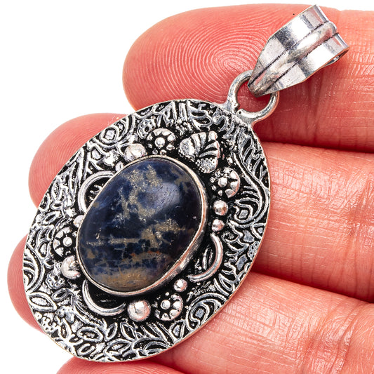 Sodalite pendant with oval blue stone in ornate silver-tone bezel, bail loop at top.