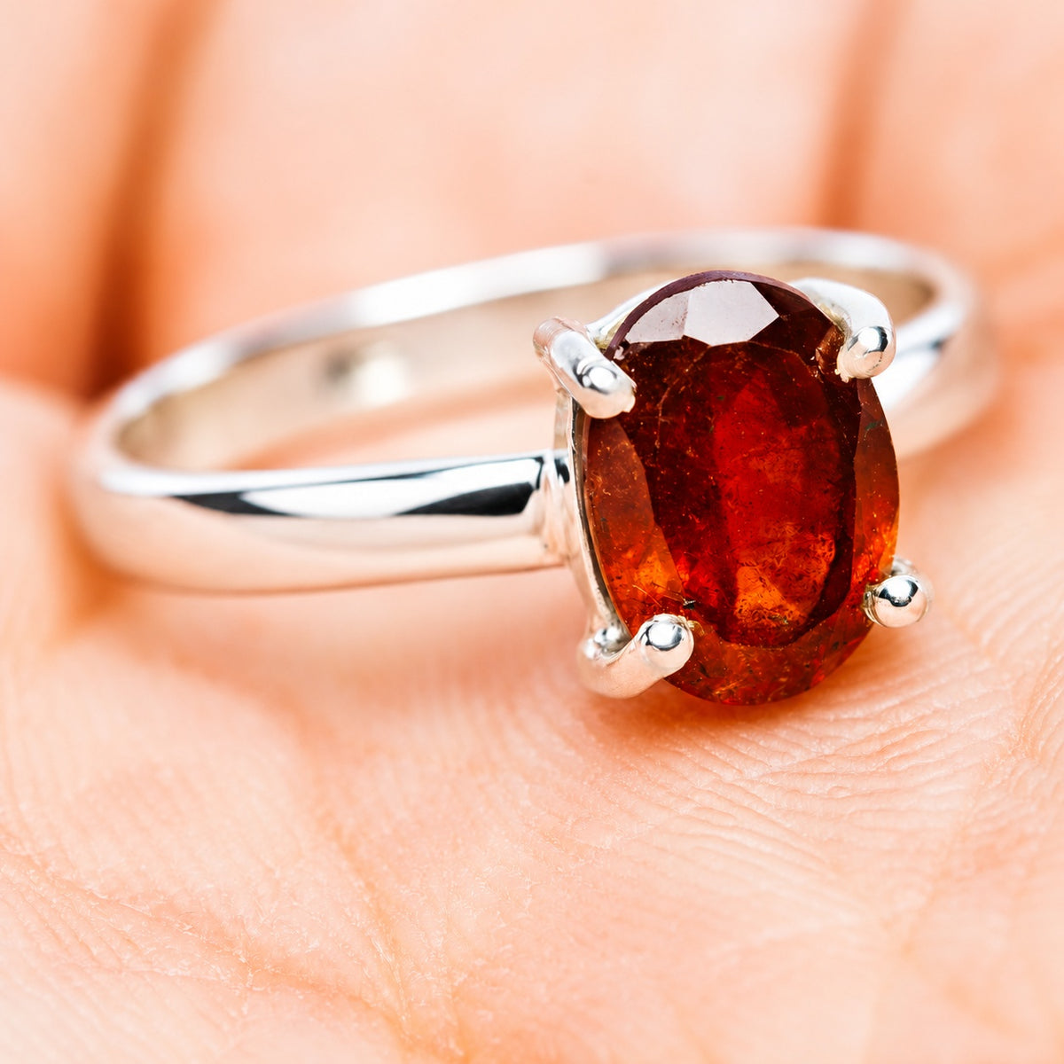 Sterling silver ring with an oval reddish-orange garnet held by four prongs