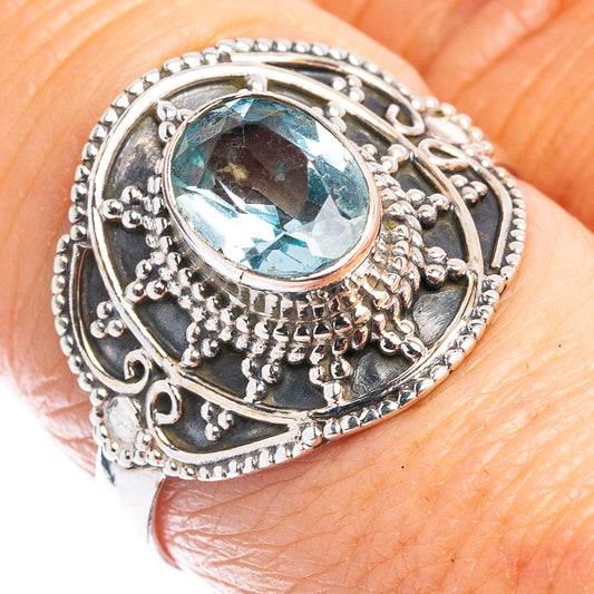 Sterling silver blue topaz ring on finger, round gemstone in detailed filigree setting
