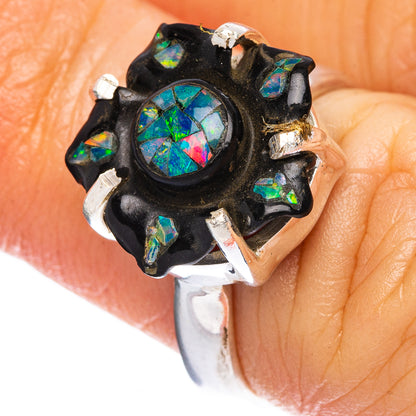 Black flower opal ring with iridescent center and silver prongs, on finger