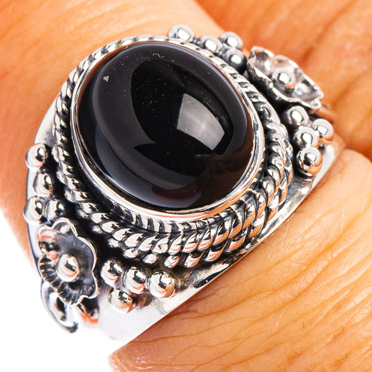 Oval black onyx ring with ornate silver bezel and textured metal band.