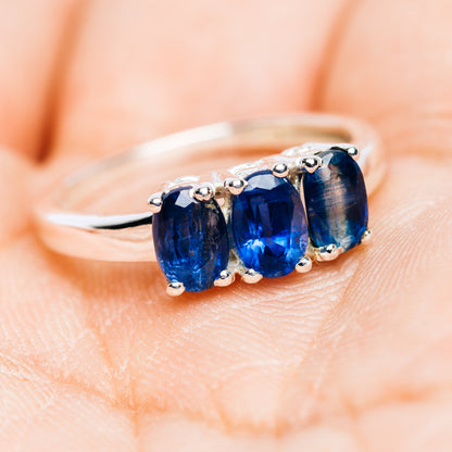Three-stone kyanite ring showing dark-blue stones and polished silver band with prongs