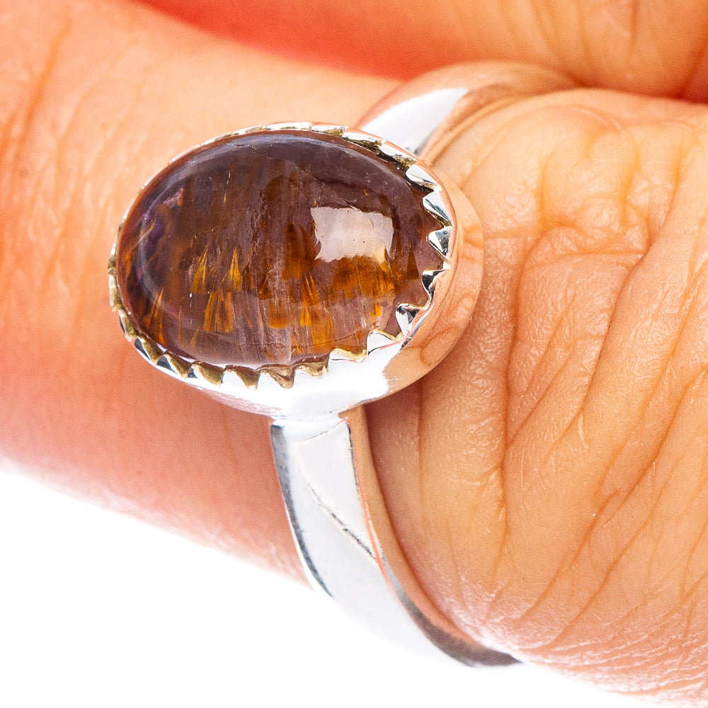 Sterling silver ring with oval dark purple cabochon and gold-toned inclusions.