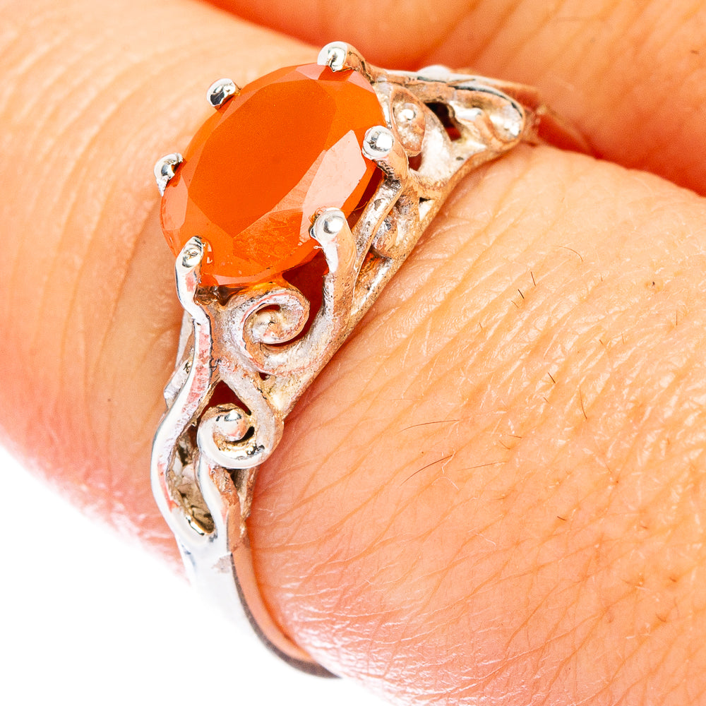 Silver carnelian ring on finger with ornate swirl setting and small clear accents