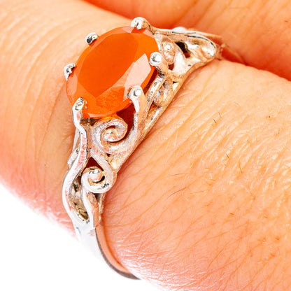 Silver carnelian ring on finger with ornate swirl setting and small clear accents