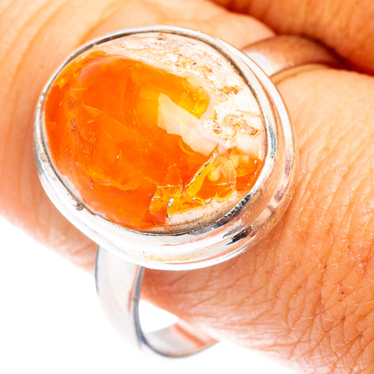 Orange fire opal stone in oval bezel on sterling silver ring, close-up on hand