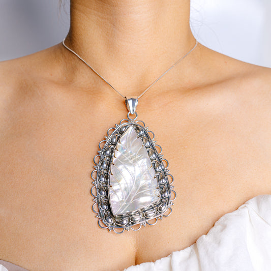 Sterling silver mother-of-pearl pendant with ornate oval frame, faceted center.