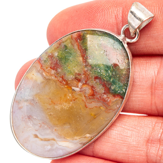 Silver-plated oval pendant with green, red, and pale mottled cabochon and bail