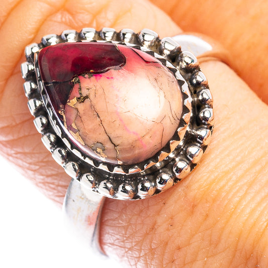 Sterling silver ring with oval red stone and beaded bezel, close-up on finger
