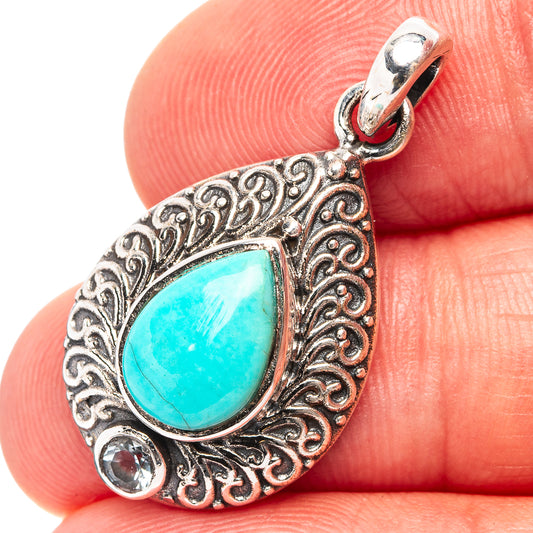 Sterling silver pendant with turquoise teardrop centerpiece and ornate scrollwork, loop top
