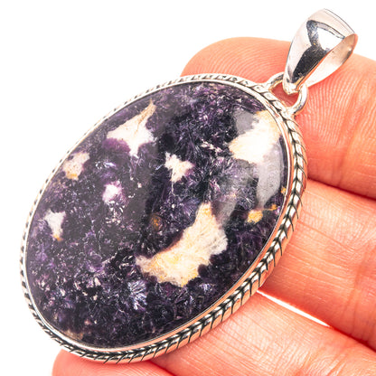 Oval sterling silver pendant with purple-and-cream Kammererite stone, held in hand
