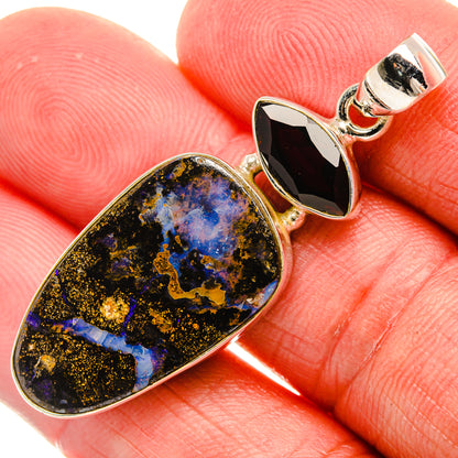 Close-up teardrop boulder opal and red garnet pendant on sterling silver
