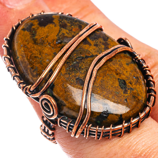 Oxidized copper wire-wrap ring with oval brown-and-gold agate and scroll details