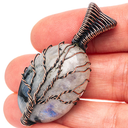 Oval moonstone pendant close-up with oxidized copper wire frame and tree pattern