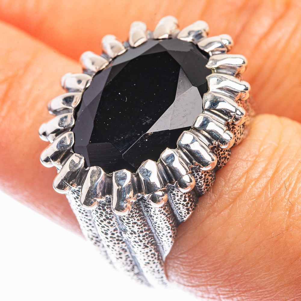 Black onyx ring with faceted oval stone and silver-tone claw prongs, textured band